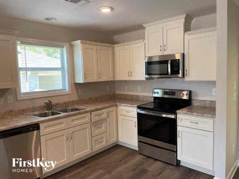 a kitchen with white cabinets and a stove and a sink