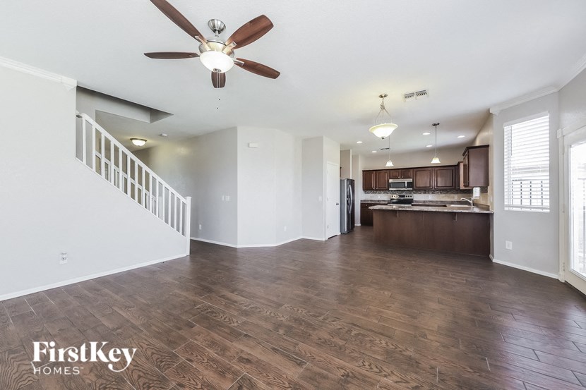 A spacious living room with wooden floors and a ceiling fan.