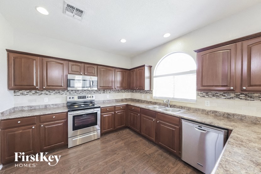 A kitchen with wooden cabinets and a stainless steel dishwasher.