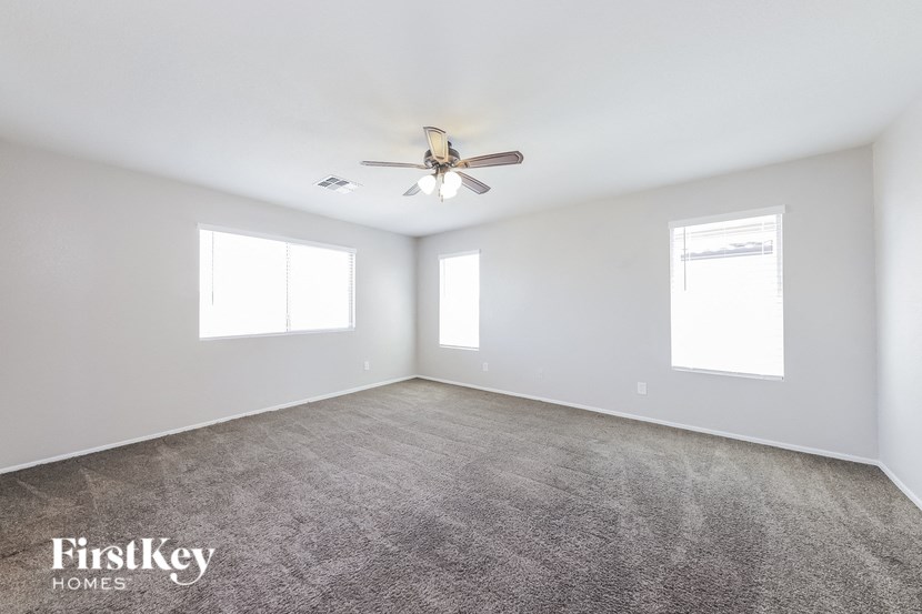 A spacious room with a ceiling fan and carpeted floor.