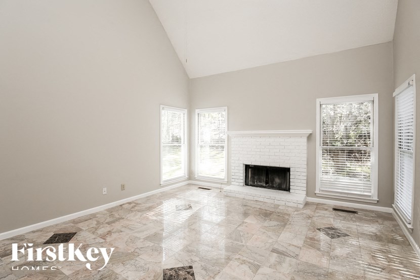 an empty living room with a fireplace and windows