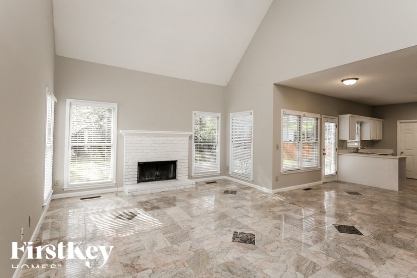 a large empty living room with a fireplace and windows