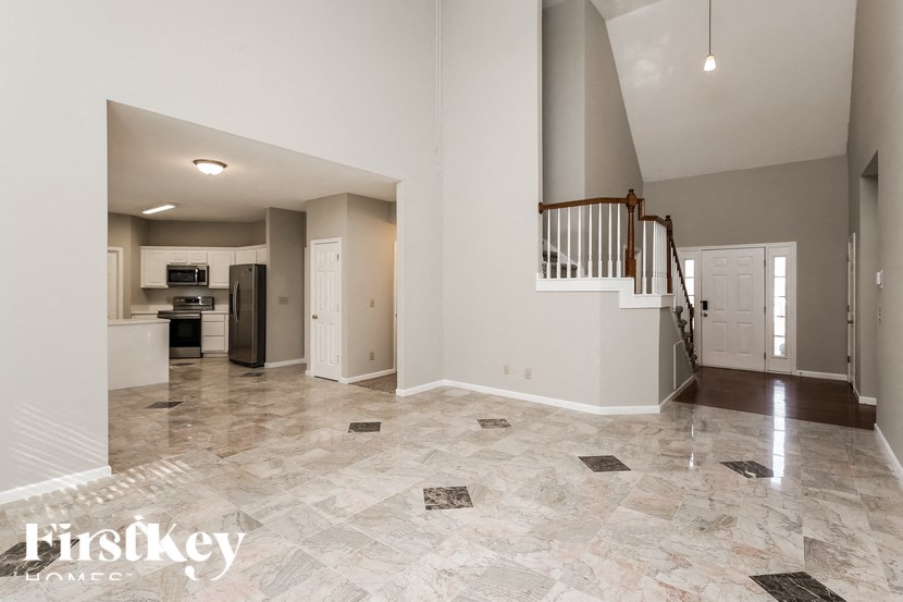 an empty living room with a staircase and a kitchen
