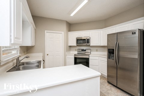 a white kitchen with stainless steel appliances and white counters