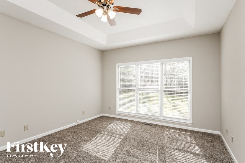an empty living room with a ceiling fan and a large window