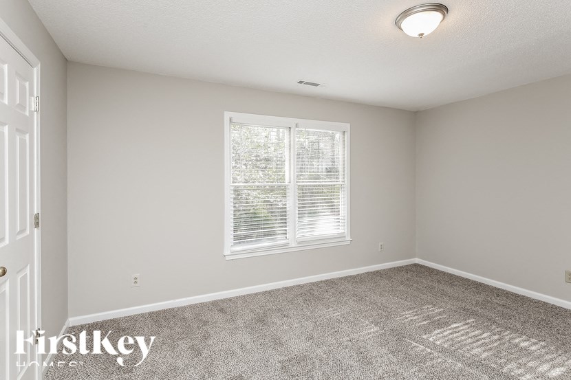 a bedroom with a large window and a carpeted floor