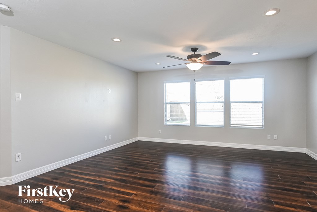 A room with a ceiling fan and wooden floors.