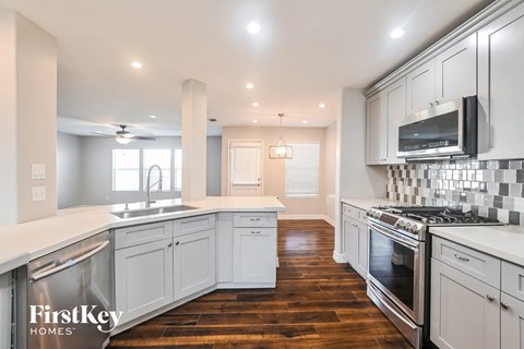A kitchen with white cabinets and a wooden floor.