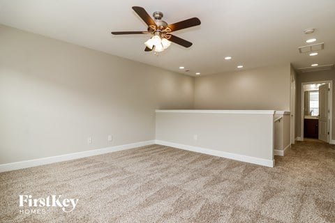 A spacious room with a ceiling fan and carpeted floor.