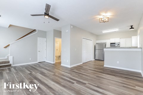 A spacious living room with a wood floor and a ceiling fan.