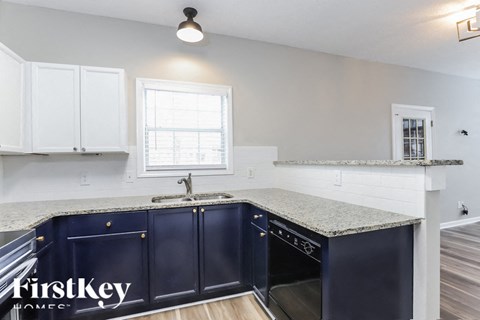 A kitchen with dark blue cabinets and a granite countertop.
