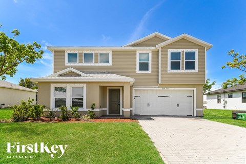 a beige house with a garage and a lawn