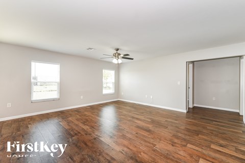 an empty living room with wood floors and a ceiling fan