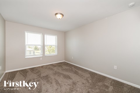 a bedroom with carpet and two windows