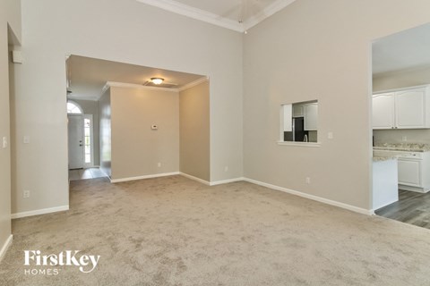 a spacious living room with carpet and a kitchen
