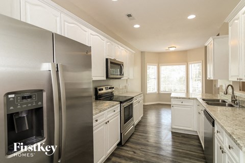 a white kitchen with stainless steel appliances and white cabinets