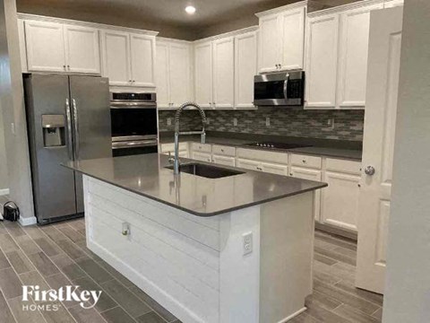 a kitchen with an island and a stainless steel refrigerator