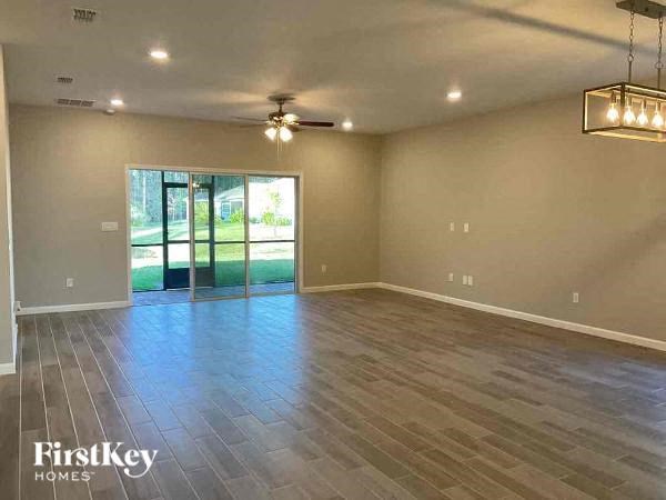 a empty living room with a ceiling fan and a sliding glass door