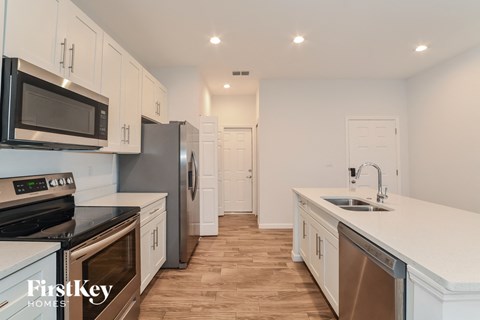 a kitchen with white cabinets and stainless steel appliances and white counter tops