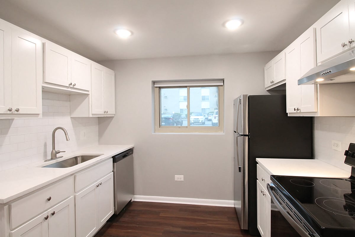 a kitchen with white cabinets and a black refrigerator