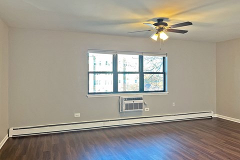 A room with a ceiling fan and a window with a view of a building outside.