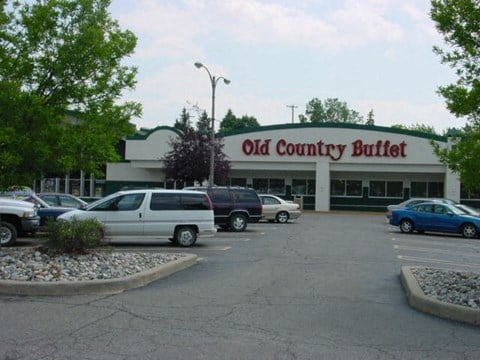 a parking lot full of cars in front of an old country buffet