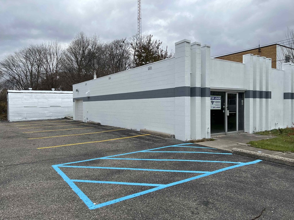 A parking lot with a white building and blue lines on the ground.