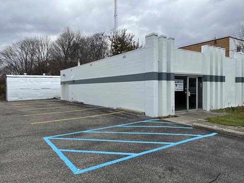 A parking lot with a white building and blue lines on the ground.