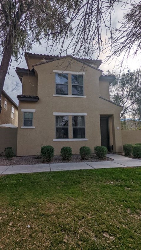A beige house with a black door and windows.