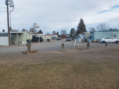 A parking lot with a blue car and a white sign.