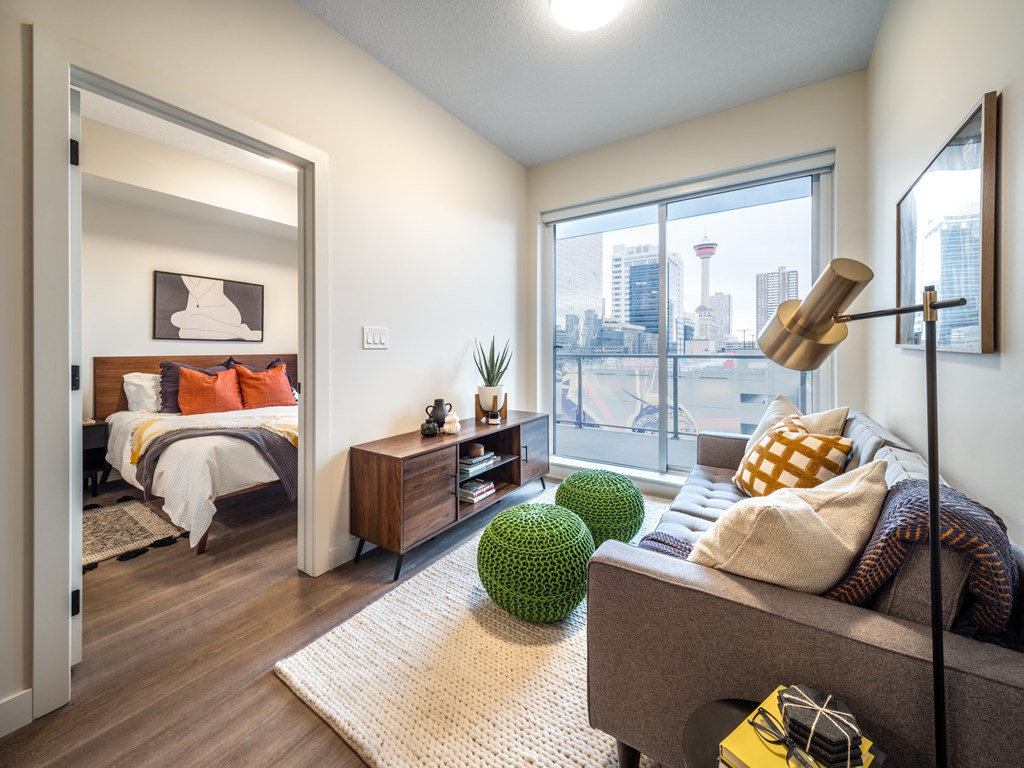 a living room with a large window and a bedroom with a bed