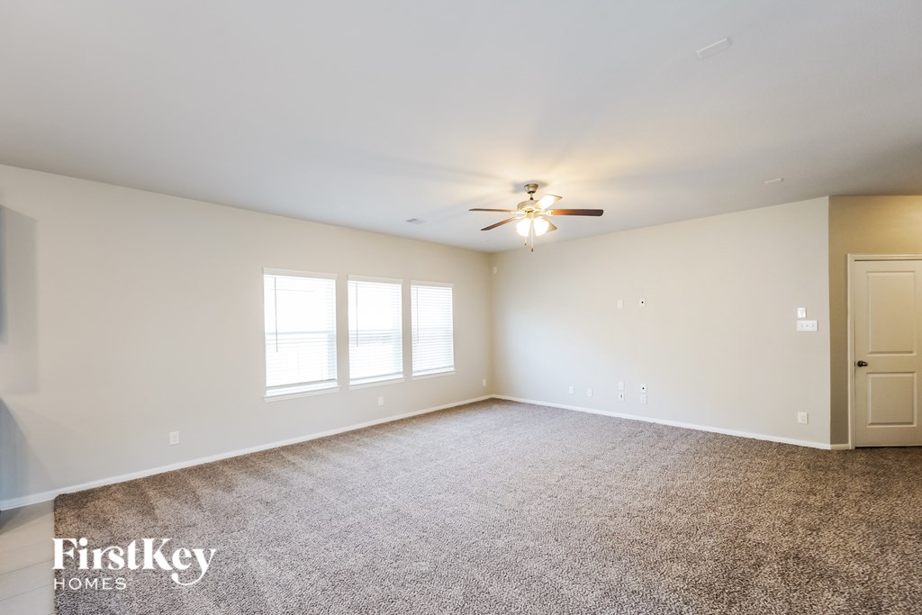 A spacious room with a carpeted floor and a ceiling fan.