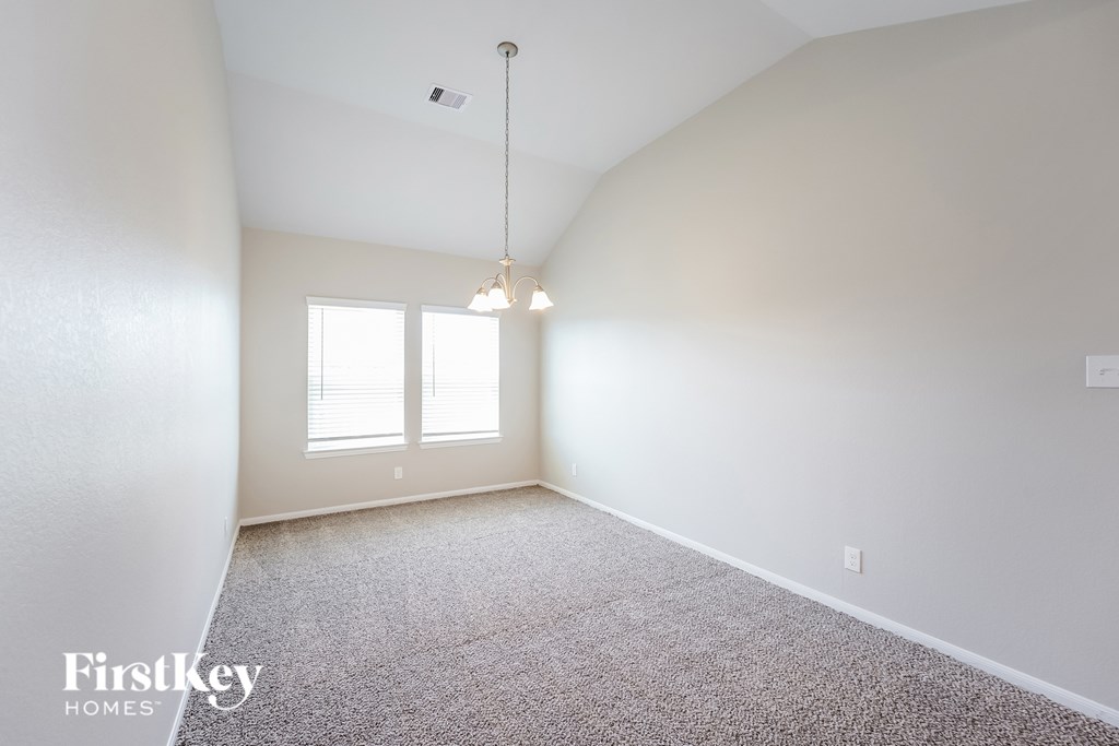 A carpeted room with a window and a light fixture.