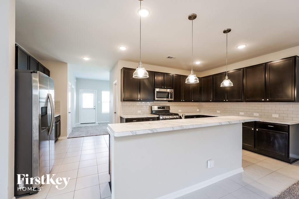 A modern kitchen with a white island and black cabinets.