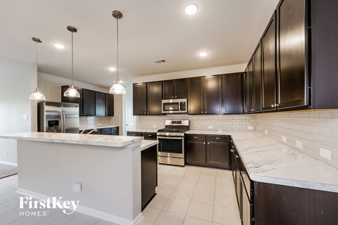 A modern kitchen with dark brown cabinets and a marble countertop.