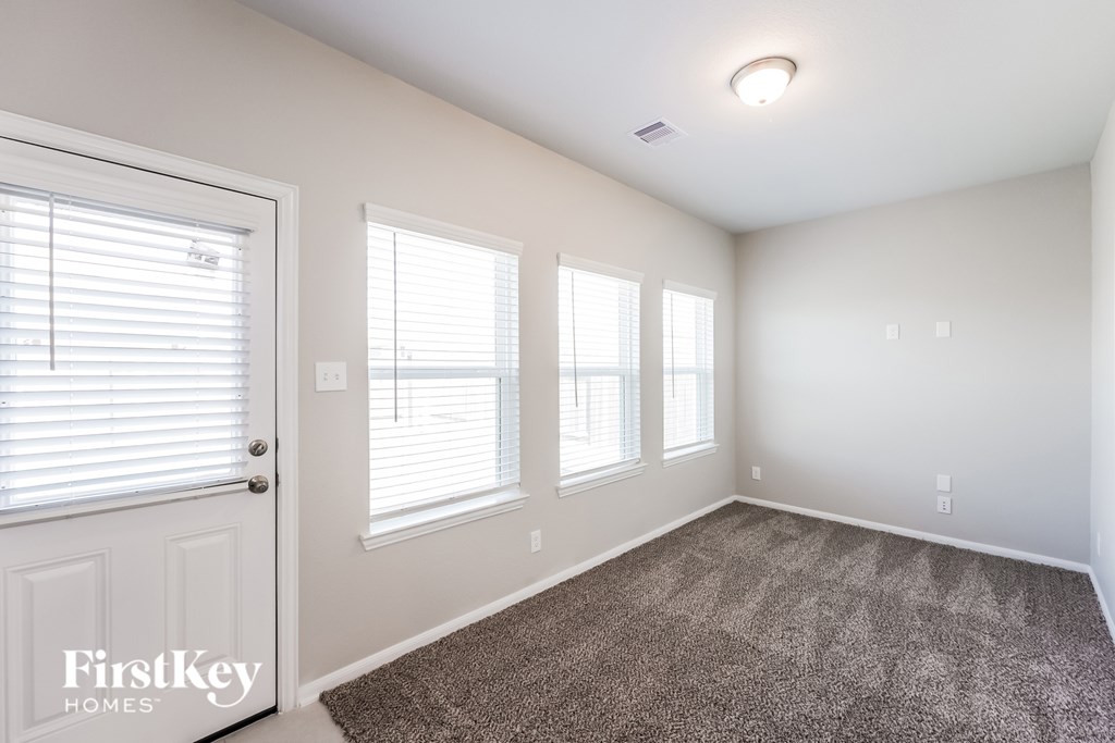 A room with a carpeted floor and three windows.