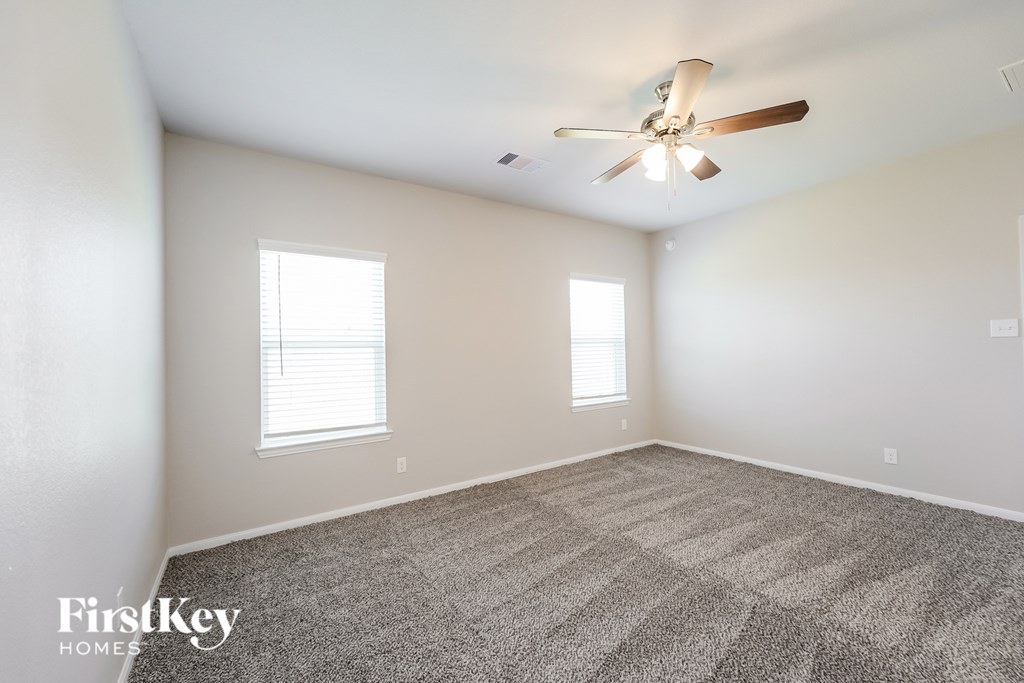 A spacious room with a ceiling fan and carpeted floor.