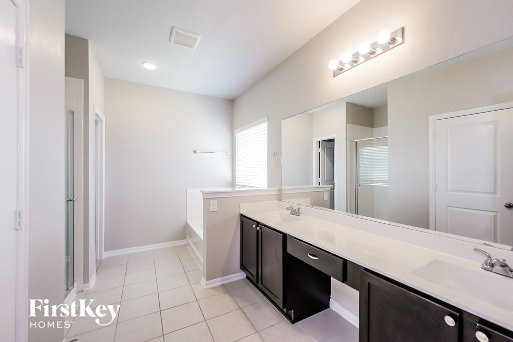 A bathroom with a white counter top and a mirror above it.