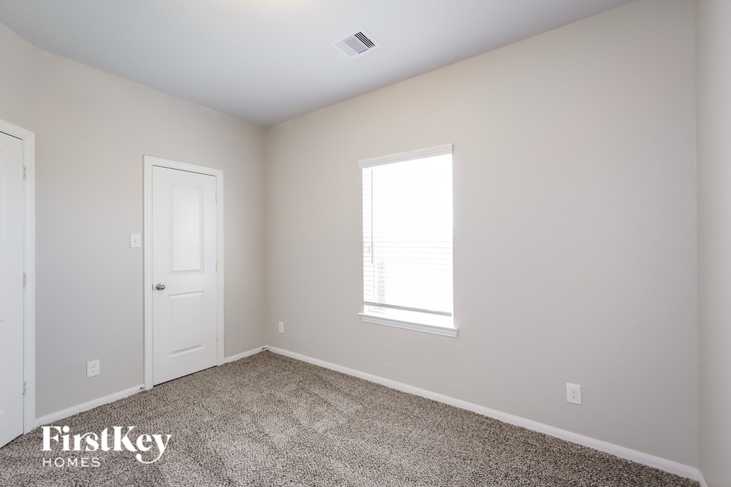 A room with a carpet floor, a window, and two doors.