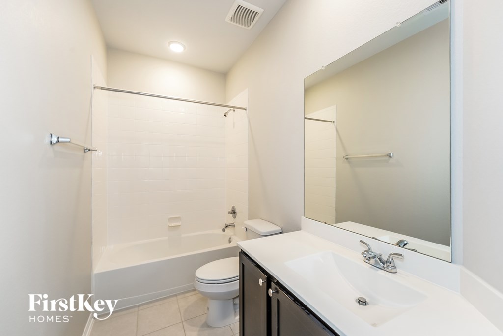 A white bathroom with a toilet, sink, and mirror.