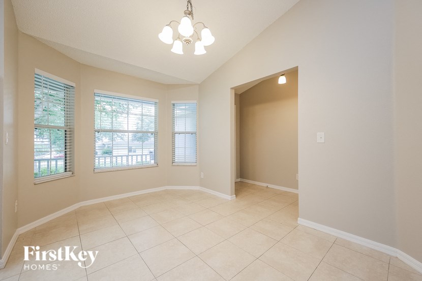 A room with a chandelier and a window with blinds.