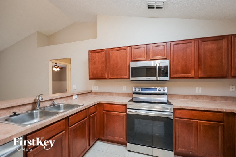 A kitchen with wooden cabinets and a stove top oven.