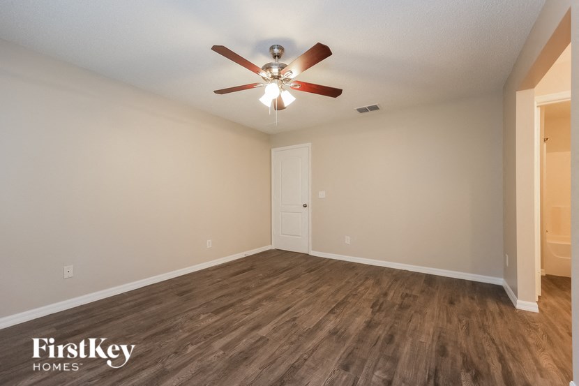 A room with a ceiling fan and wooden flooring.