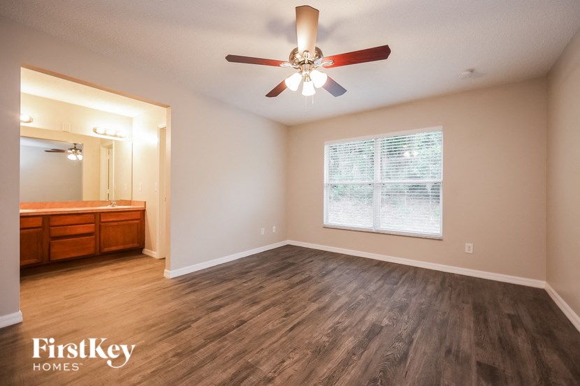 A room with a ceiling fan and wooden flooring.