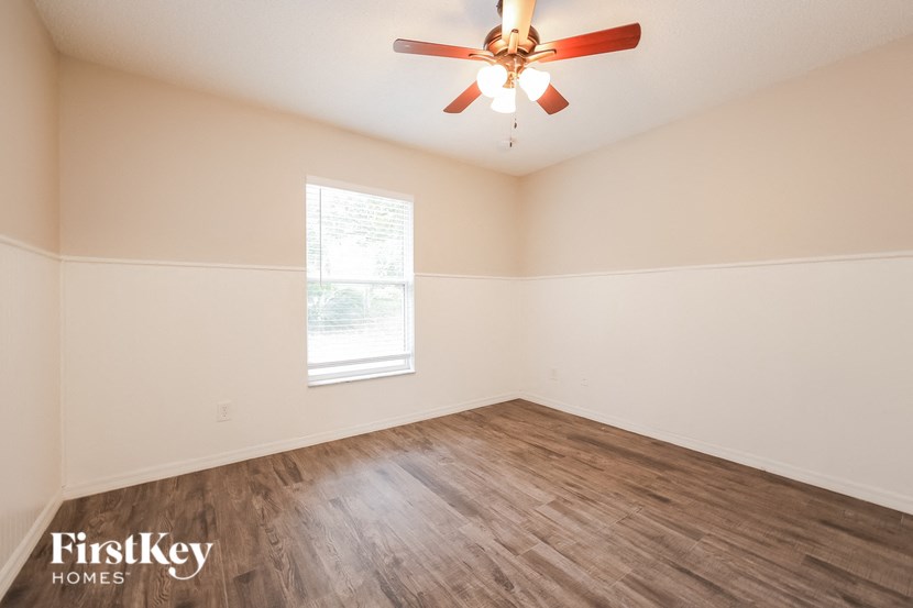 A room with a ceiling fan and wooden flooring.