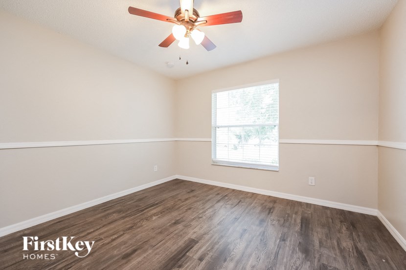 A room with a ceiling fan and wooden flooring.