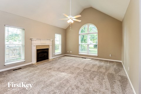 A spacious room with a fireplace and a ceiling fan.