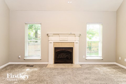 A living room with a fireplace and two windows.