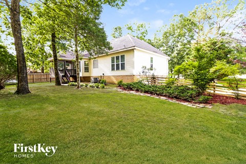 A house with a well-kept lawn and trees in the background.