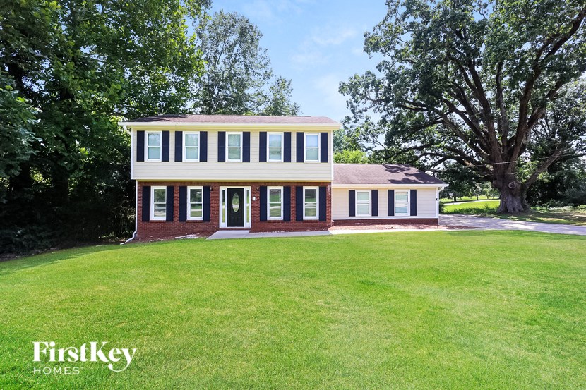 a white and brick house with a lawn and trees